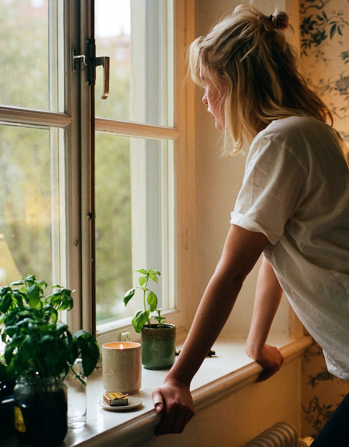 a woman looks out the window on a gloomy gray day while a ce 185dee258cd629ef391548b91bb25f47